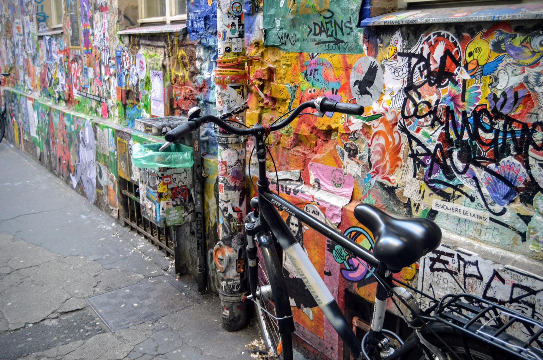 Bicicleta apoyada junto a un muro cubierto de arte urbano en el Haus Schwarzenberg de Berlín, fotografía de Tomeu Fiol