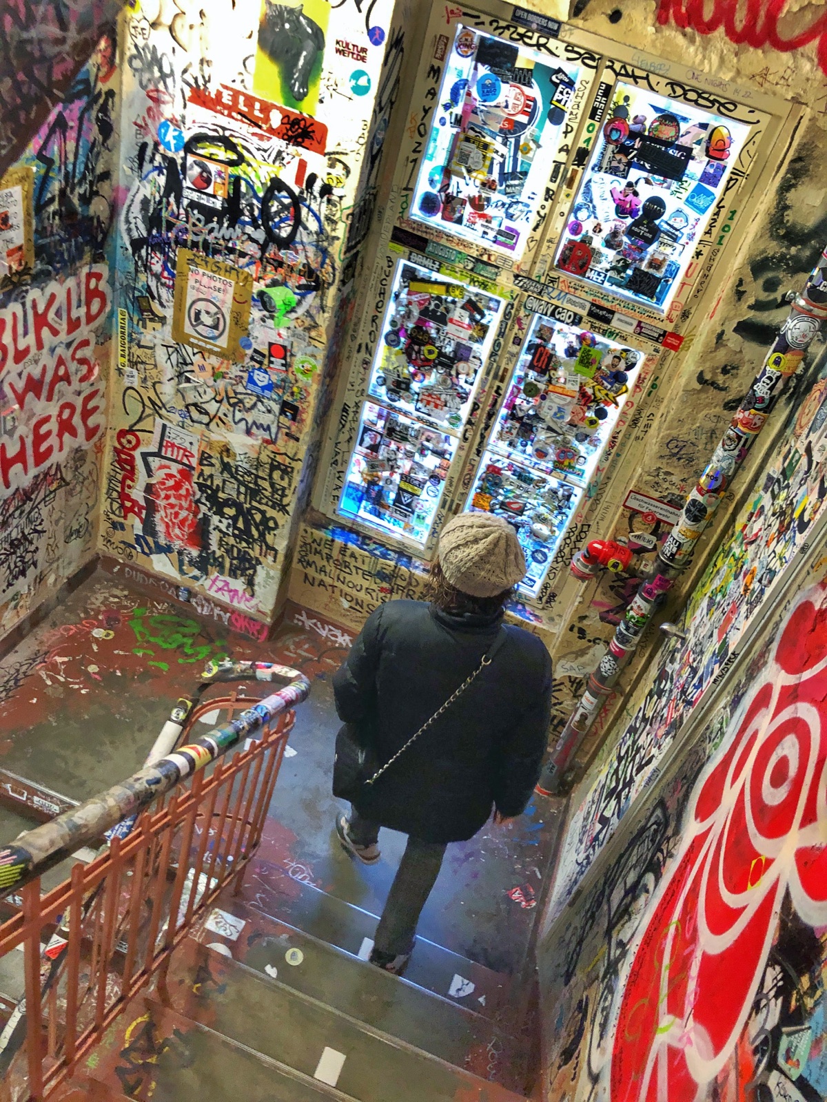 Visitante baja por las escaleras intervenidas con pegatinas y grafitis del Haus Schwarzenberg de Berlín, fotografía de Tomeu Fiol